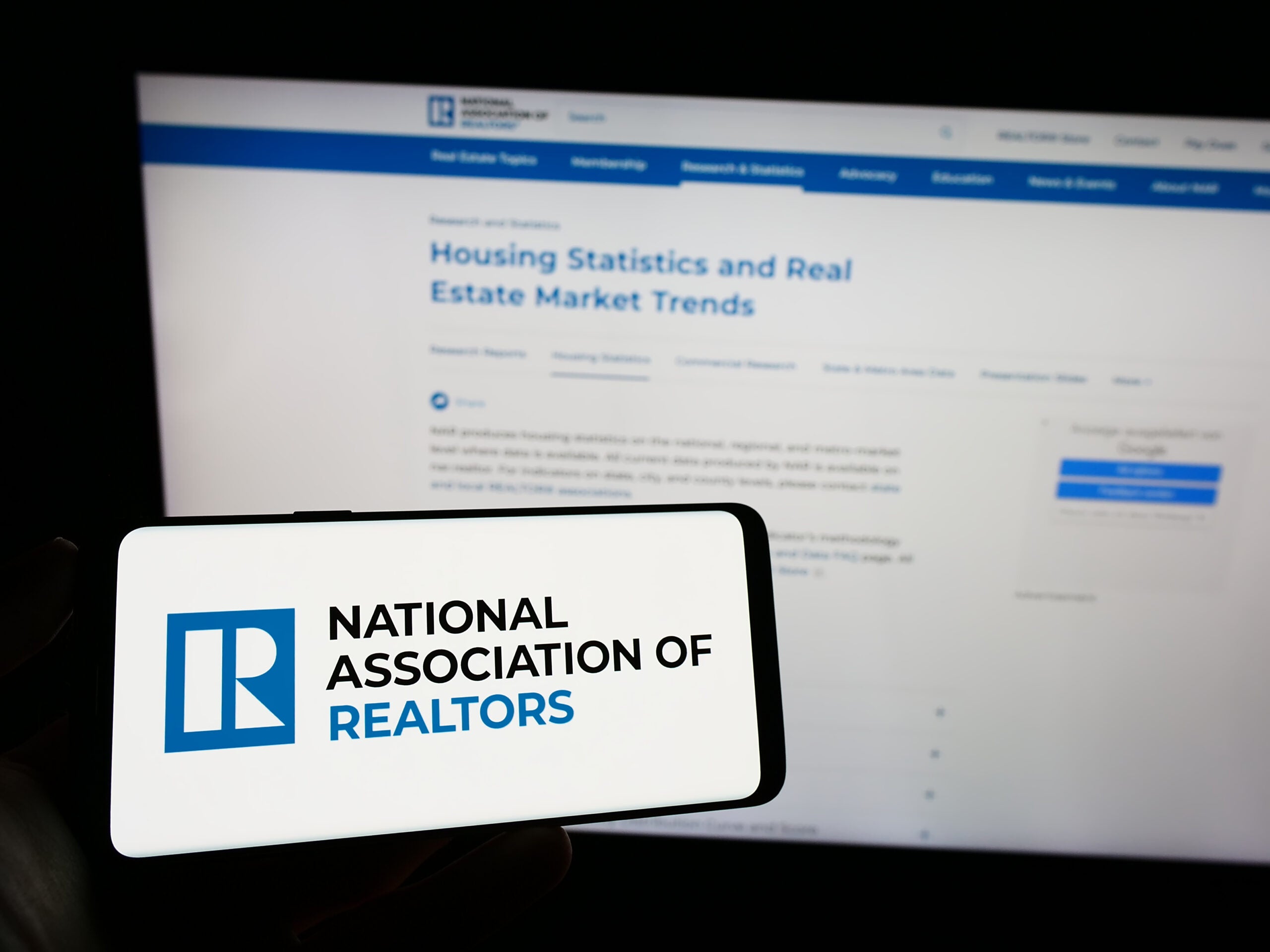 The NAR, or National Association of Realtors, logo on a phone before a computer screen.