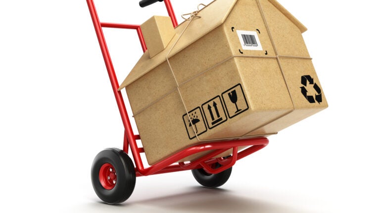 Delivery or moving houseconcept. Hand truck with cardboard box as home isolated on white. 3d
