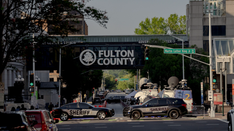 A bridge emblazoned with the words "Fulton County" stands over a busy intersection