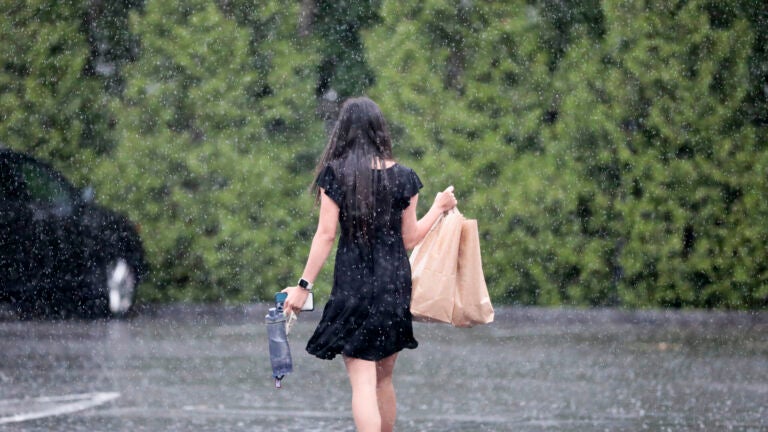 Boston weather - After shopping at the Fruit Center Marketplace (cq), in Milton, a woman heads to her vehicle, in a downpour.