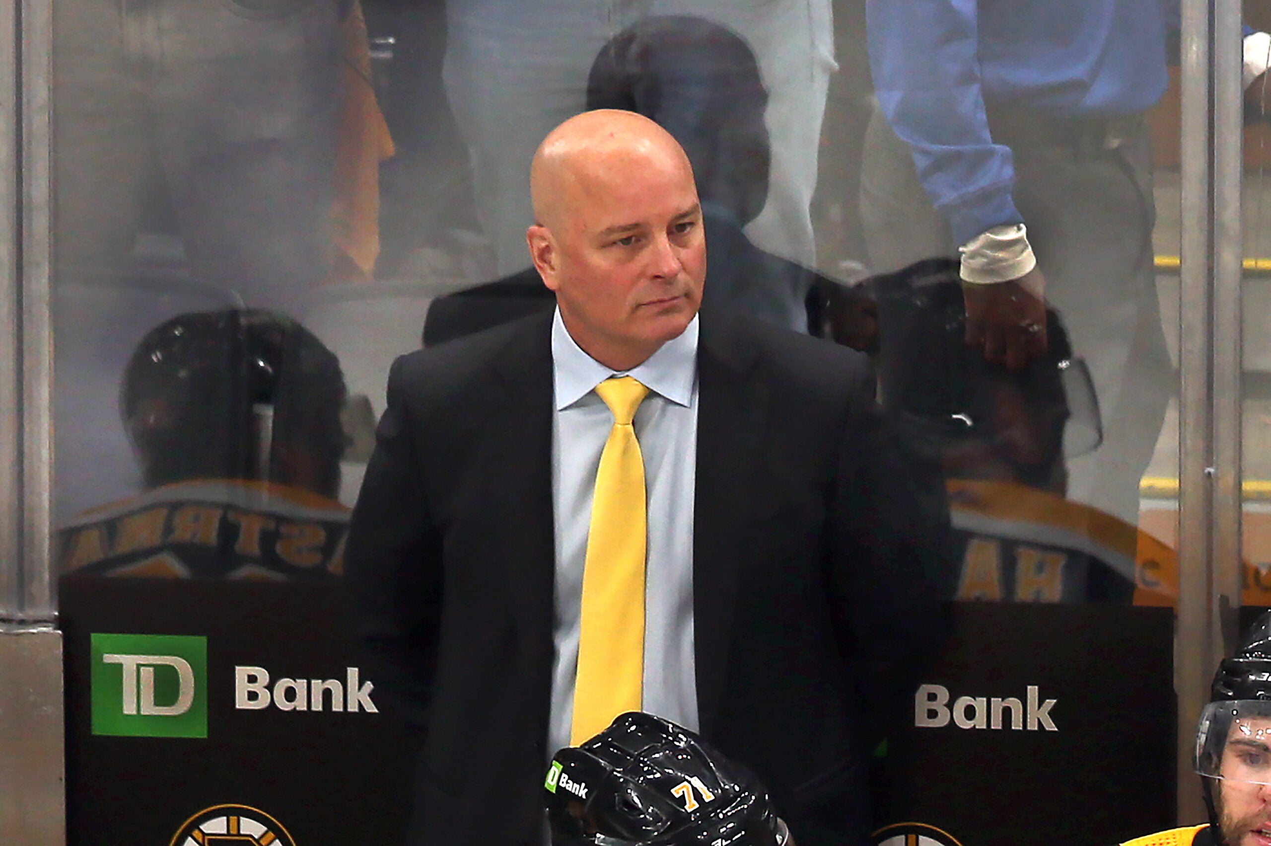 Bruins coach Jim Montgomery stands at the bench as Florida players celebrate on the ice after they beat the Bruins ion overtime.