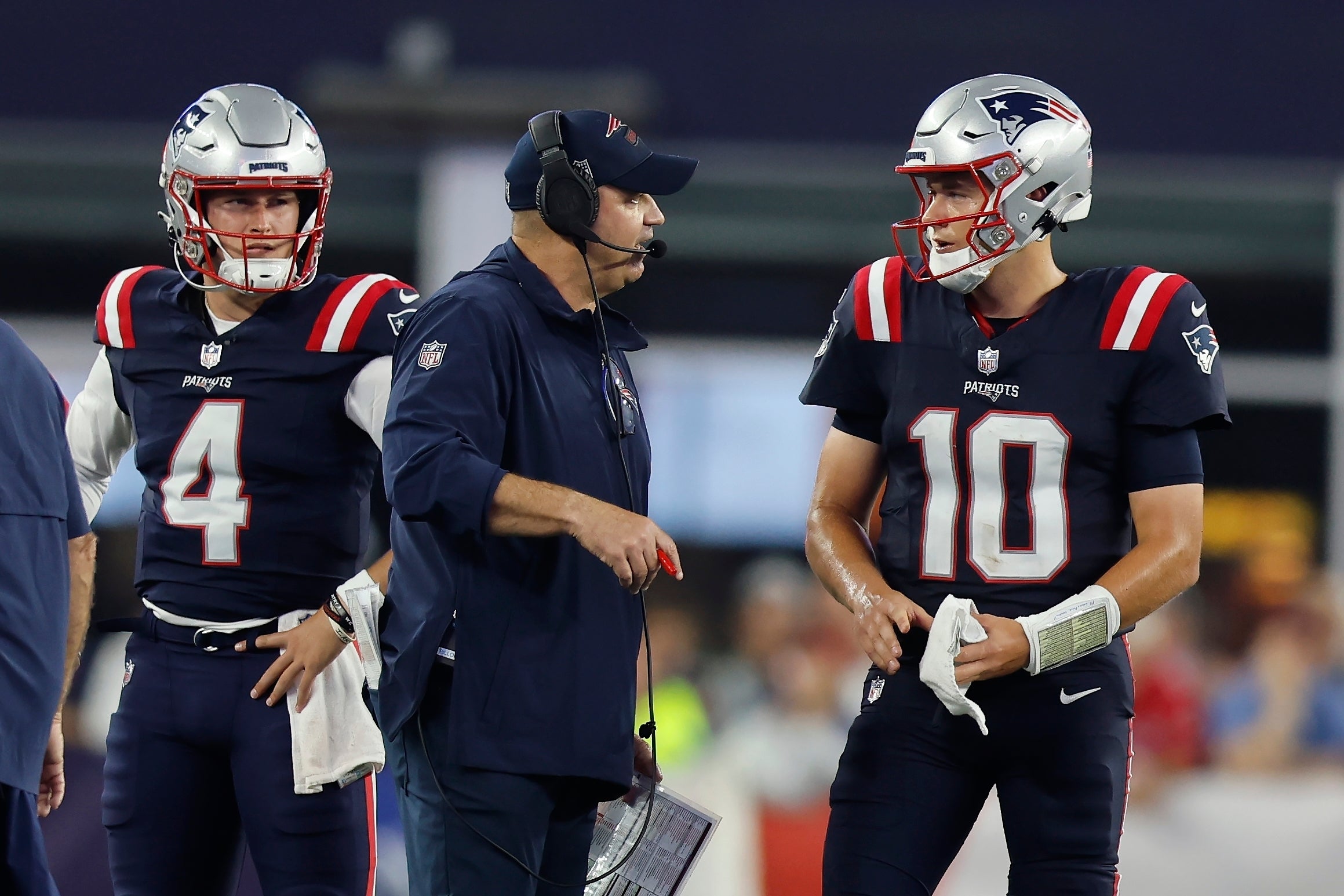 New England Patriots offensive coordinator Bill O'Brien speaks with quarterback Mac Jones (10) as quarterback Bailey Zappe (4) looks on during the second half of an NFL football game against the Philadelphia Eagles, Sunday, Sept. 10, 2023, in Foxborough, Mass.