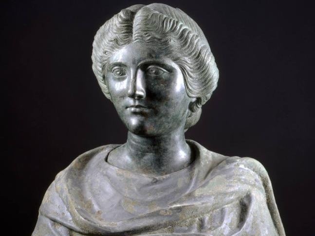 The bust of a young woman with a heavy-lidded gaze and hair carefully combed into waves.